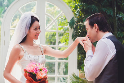 Man kissing bride hand