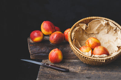 Close-up of fruits in basket on table against black background