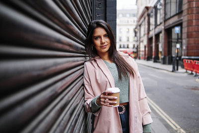 Portrait of smiling young woman standing in city