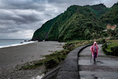 Woman walking on coastal beach on rainy day