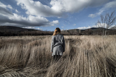 Rear view of woman standing on field against sky