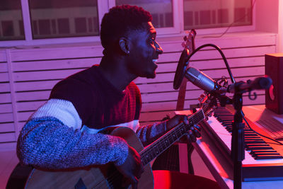 Side view of young man playing guitar