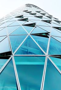 Low angle view of glass building against blue sky