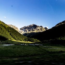 Scenic view of lake and mountains against clear blue sky