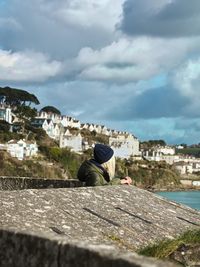 Side view of woman by retaining wall against sky