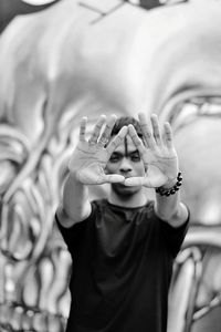 Portrait of young man gesturing against mural on wall