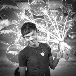 Portrait of smiling young man against illuminated lights