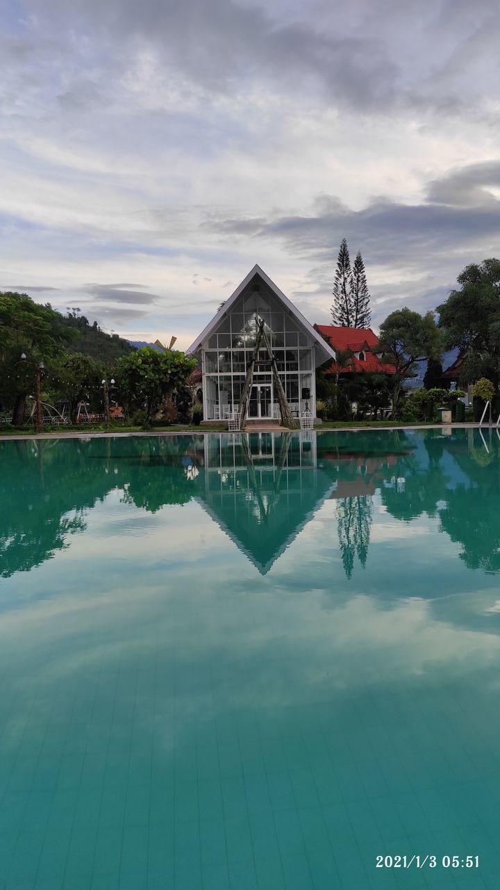 REFLECTION OF BUILDING IN SWIMMING POOL AGAINST SKY