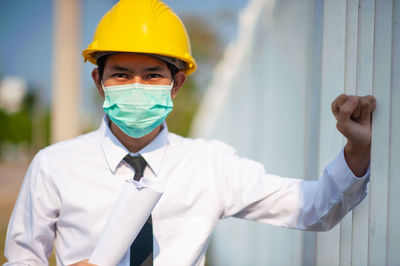 Midsection of man wearing hardhat while standing against wall