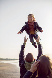 Father and son in leather jackets in autumn walking in nature near the bay on the beach with sand