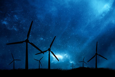 Low angle view of windmills against starry sky at night