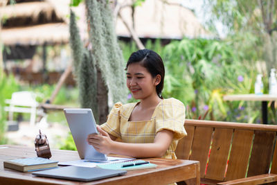 Portrait of young woman using mobile phone while sitting on table