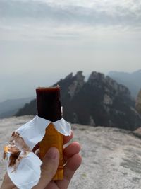 Person holding ice cream against mountains