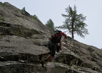 Full length of man climbing rock on mountain against sky