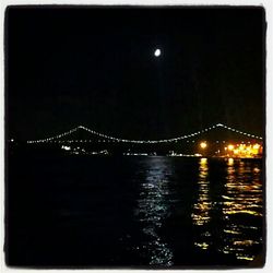 Illuminated bridge over river at night