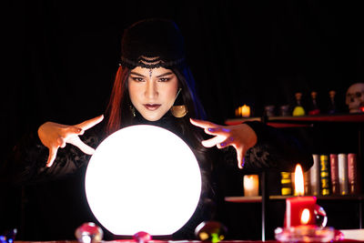 Young woman wearing mask against black background