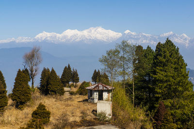 House amidst trees and kanchenjunga mountain range against sky