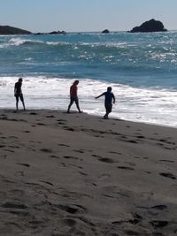 People on beach by sea against sky