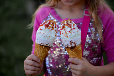 Midsection of girl holding ice cream cones while standing at park