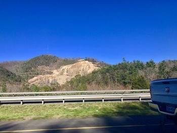 Road by mountain against clear blue sky