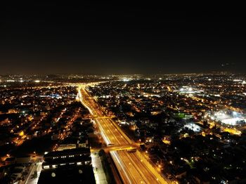 High angle view of illuminated street amidst buildings in city at night