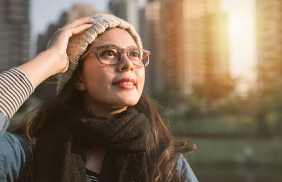 Close-up of young woman wearing eyeglasses against city