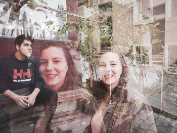 Portrait of happy young woman against window