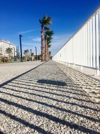 Surface level of footpath against clear blue sky