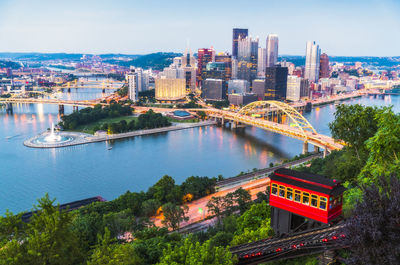 High angle view of bridge over river by buildings in city against sky