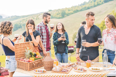 Friends enjoying drinks while standing in outdoors party