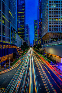 Light trails on city street amidst buildings at night