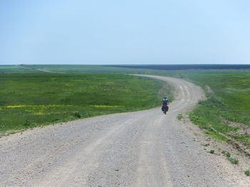 Rear view of people riding motorcycle on road