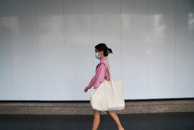 Full length of woman standing against wall