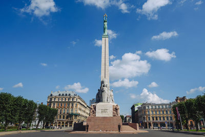 Statue in city against cloudy sky