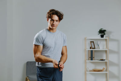 Portrait of young man standing against wall