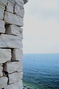Stack of rocks by sea against sky