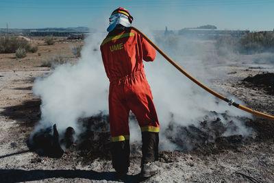 Rear view of fire fighter spraying water