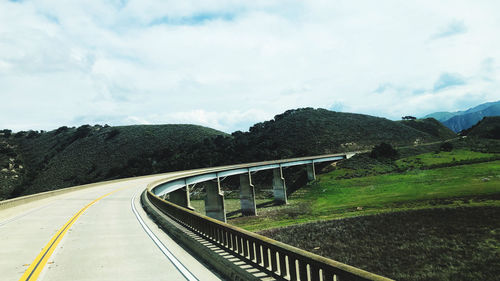 Empty road leading towards mountain against sky