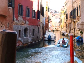 Boats moored in canal with buildings in background