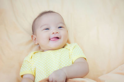 Portrait of cute baby girl lying on bed