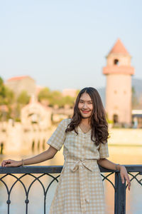 Portrait of smiling woman standing against railing