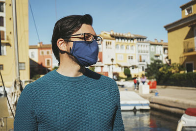 Portrait of young man standing against buildings in city