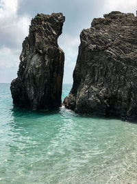 Rock formation in sea against sky