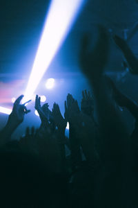 Silhouette raised hands of women and men dancing at nightclub