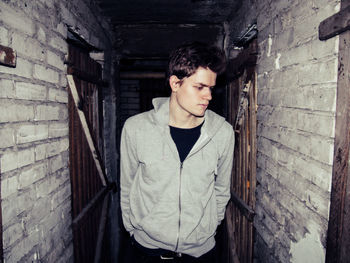 Handsome man standing in narrow alley of abandoned building