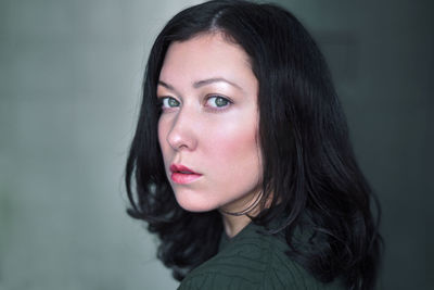 Close-up portrait of beautiful woman against wall