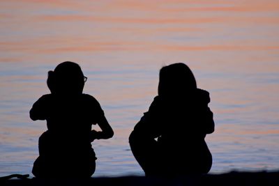 Silhouette of man photographing at sunset