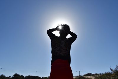 Low angle view of woman standing against clear blue sky