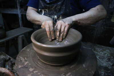 Midsection of man making pottery in workshop