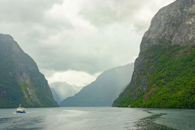 Scenic view of sea by mountains against sky